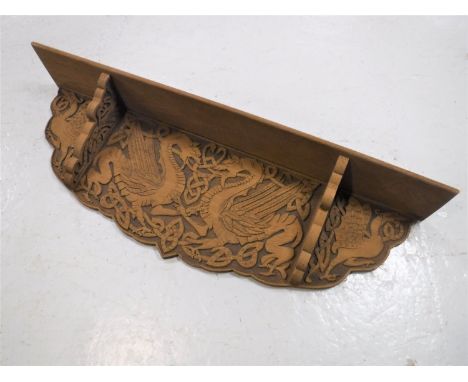 A carved oak wall shelf depicting dragons 