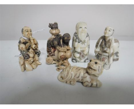 A Japanese ivory netsuke in the form a seated man smoking a pipe, together with three further ivory and bone netsukes and an 