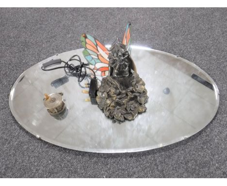 An oval unframed mirror, Tiffany style table lamp of a flower fairy and a vintage fishing fly reel 