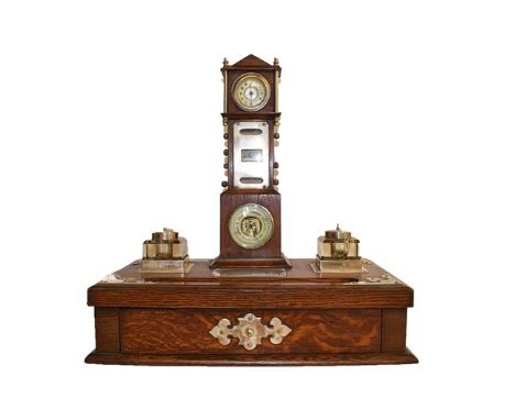 A silver plate mounted oak desk stand, circa 1900, surmounted by a miniature longcase clock, with timepiece perpetual calenda