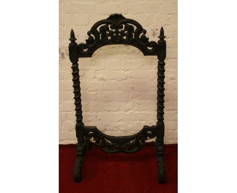 An antique carved oak firescreen raised on barleytwist supports.