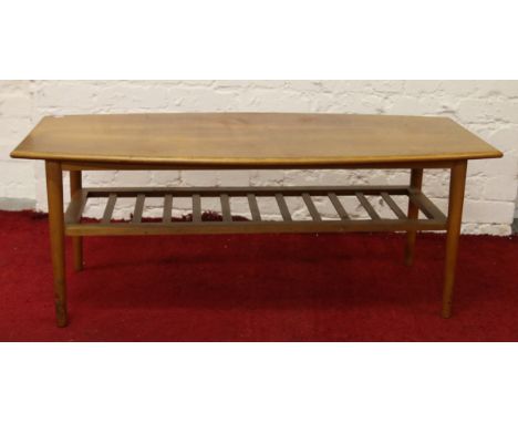 A light oak coffee table with magazine shelf raised on turned legs.