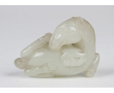 A Chinese pale celadon jade pendant, probably Qing dynasty, finely carved and pierced in the form of a recumbent horse, lengt