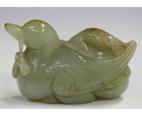 A Chinese celadon jade carving of a duck, late Qing dynasty, modelled grasping a branch in its beak, the stone of celadon ton