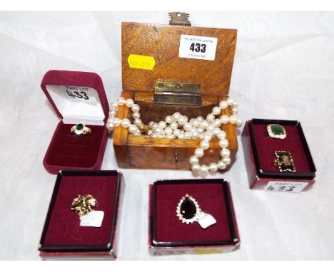 A miniature wooden chest containing two pearl necklaces and five yellow metal good quality rings predominantly by Seta (5)