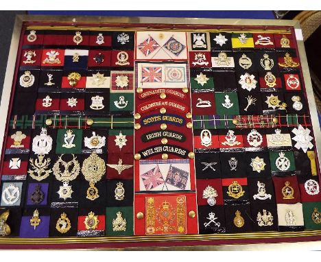 A framed collection of approximately 76 regimental cap badges, patch badges and similar, all different, frame size 64cm x 84.