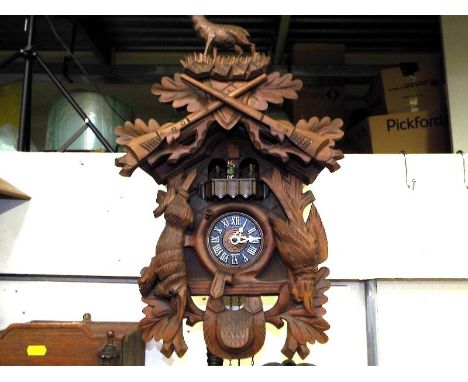 A decorative wall mounted cuckoo clock, two pine cone weights, carved animals to case and top pediment, dancing figures on a 