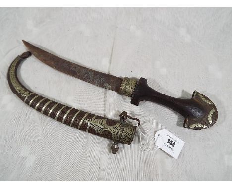 An Eastern style curved bladed dagger with brass scabbard and inlaid white metal, approximate length 42cm