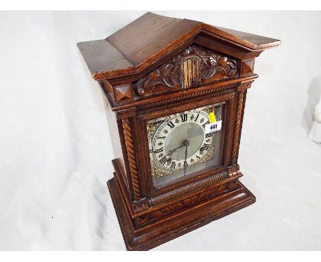 A bracket style mantel clock, the hour and half past gong strike movement by Jughans, the carved beech case of architectural 