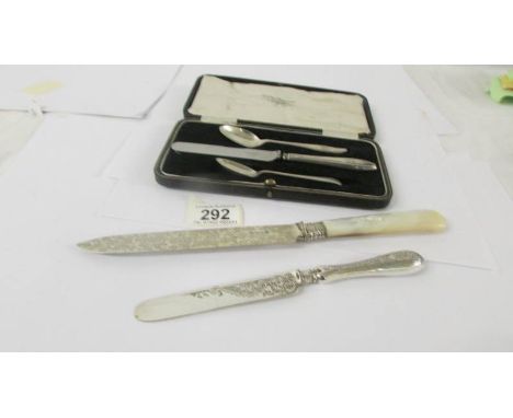 A silver cake knife with mother of pearl handle, a silver butter knife, two silver teaspoons and silver handled knife.  
