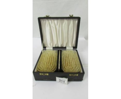 An as new cased pair of silver backed brushes with comb.