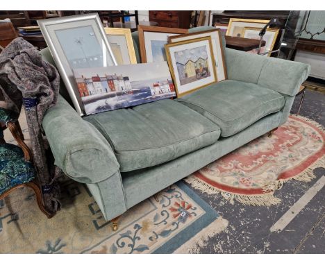 A WESLEY BARRELL THREE SEAT SETTEE UPHOLSTERED IN PALE BLUE, THE LEGS ON BRASS CASTER FEET