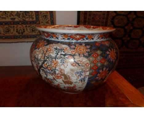 A late 19th century Japanese Imari fish bowl, the blue ground with flowerhead decoration interspersed by pictorial reserves d