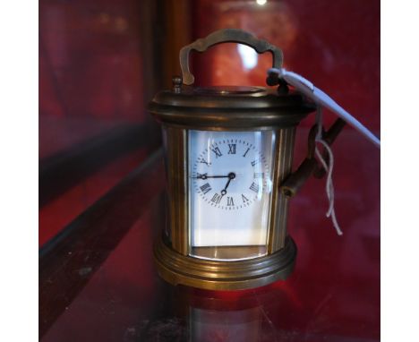 A brass oval form miniature carriage clock with enamelled Roman numeral dial  