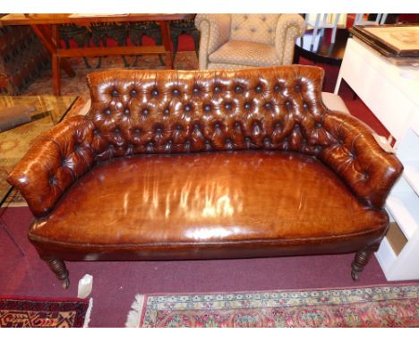 A Victorian sofa of smaller proportions upholstered in buttoned tan leather with studded detail raised on turned support sand