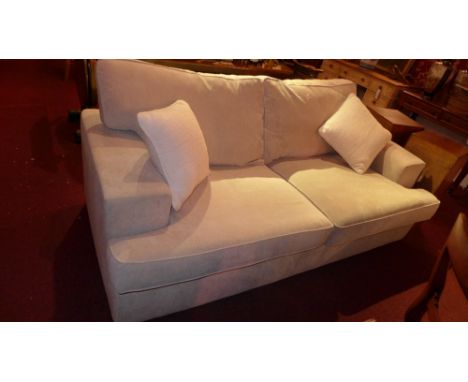 A contemporary designer two seater sofa of angular form upholstered in beige fabric raised on block supports with additional 