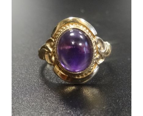 CABOCHON AMETHYST SINGLE STONE RINGon nine carat gold shank with scroll decorated shoulders, ring size O