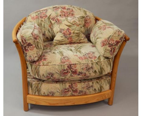 An Ercol ash framed tub style cottage chair, with loose floral pattern cushions.