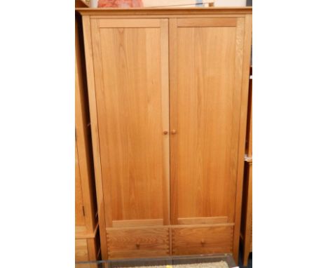 A modern light oak wardrobe, enclosed by two doors with a plain moulded cornice and fitted with two drawers below, 110cm wide