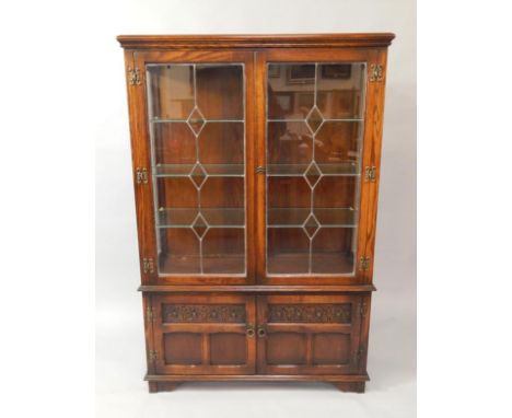 An Old Charm medium oak display cabinet, with three plate glass shelves enclosed by two leaded light doors and with cupboard 
