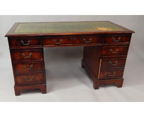 A reproduction mahogany Georgian style kneehole desk, with inset green leather top and fitted with three frieze drawers on pl