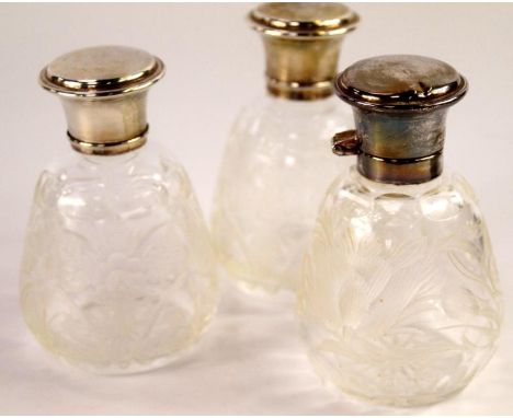 Three cut glass and silver mounted scent bottles, with cut floral decoration and one bottle with a hinged silver lid, Sheffie