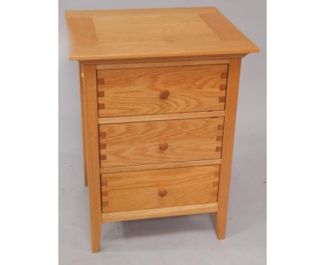 A modern light oak three drawer bedside pedestal.