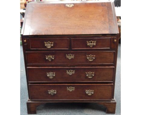 A George III mahogany bureau, with crossbanded fall flap revealing a fitted interior resting on lopers over two short and thr