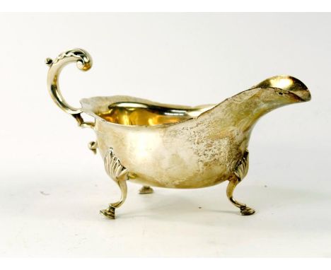 A George V silver sauce boat, of early Georgian design with acanthus leaf capped scroll handle, and three hoof feet, Sheffiel