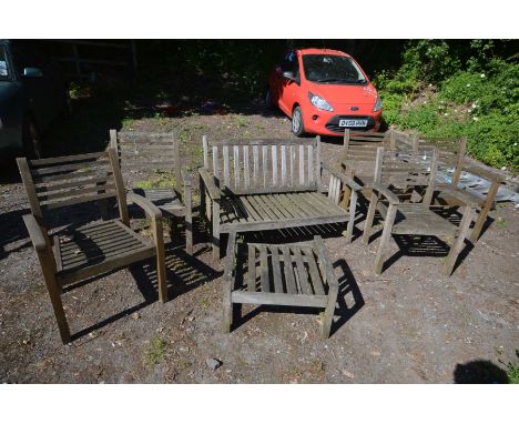 A MATCHED SEVEN PIECE TEAK GARDEN SET, comprising a settee, five armchairs and a pouffe (Sd and rickety)