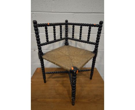 AN ARTS AND CRAFTS EBONISED BOBBIN TURNED CORNER CHAIR, with a rush seat (over painted)