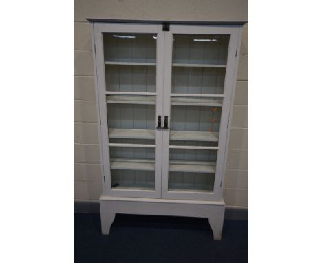 A WHITE PAINTED GLAZED TWO DOOR BOOKCASE, Art Nouveau handles, enclosing four fixed shelves, on high bracket feet, width 118c