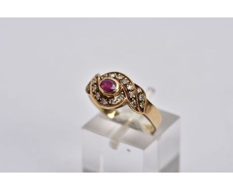 A YELLOW METAL RUBY AND DIAMOND CLUSTER RING, centring on an oval cut ruby, within a single cut diamond detailed cross over s