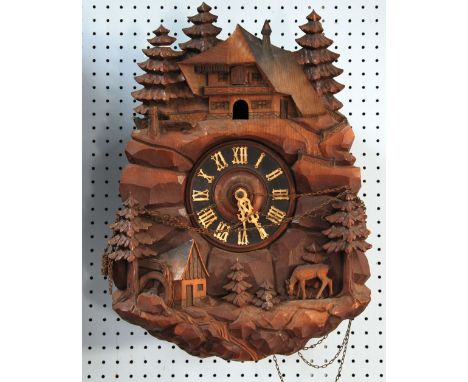 A BLACK FOREST/SWISS CARVED WOODEN CASED CUCKOO CLOCK with three train movement striking on a coiled gong and playing a tune 