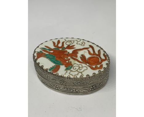 AN ORNATE WHITE METAL BOX WITH INTERNAL MIRROR AND AN ENAMEL LID WITH ORIENTAL DRAGON DESIGN 