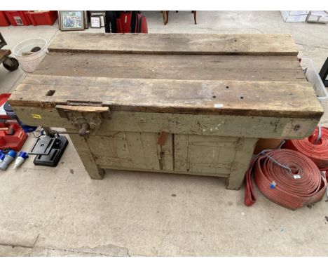 A LARGE VINTAGE WORK BENCH ENCLOSING TWO LOWER CUPBOARD DOORS AND A RECORD BENCH VICE 