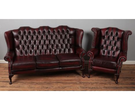 An Oxblood Chesterfield style red wingback chair and matching wingback three seater sofa.  