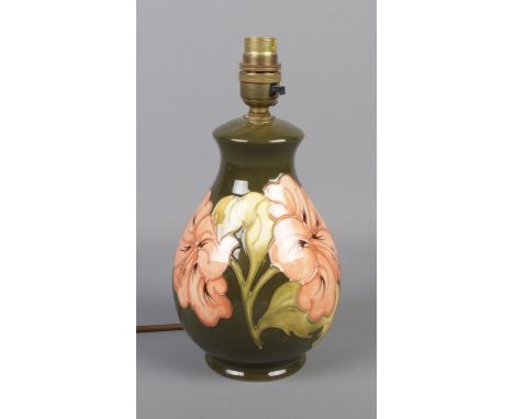 A Moorcroft pottery table lamp in the Hibiscus pattern on a green background. Approx 26cm high.  