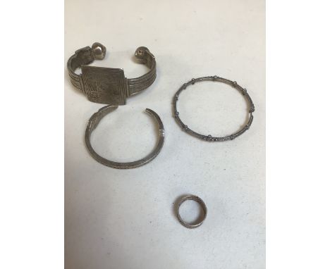 A Mauritanian engraved heavy bangle, a child's bangle, one other bangle and a filigree decorated ring.