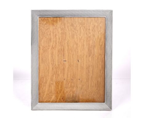 A silver photo frame of rectangular form with engine turned decoration
