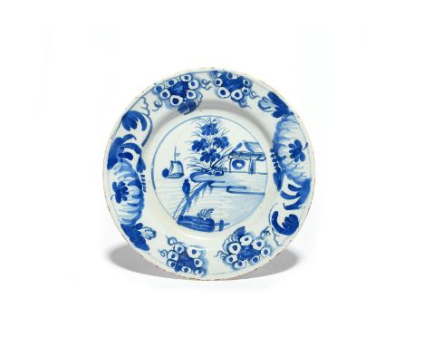A rare Glasgow delftware plate  c.1760, painted in blue with a boat at sail before a small building, the rim with leaves and 