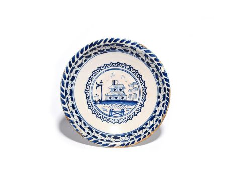A delftware charger  c.1700, probably Bristol, painted in blue with a two-storey building within a circular panel, within a b