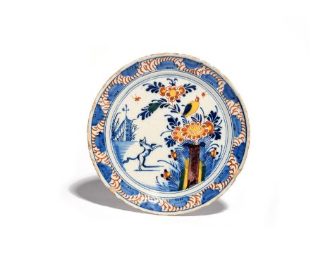 A delftware plate  c.1720, probably London, painted with a dog or fox raised on its back legs beneath a yellow bird perched o