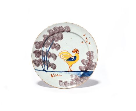 A Bristol delftware 'Farmhouse' plate  c.1720-30, painted with a bold cockerel in yellow, blue and red, standing between spon