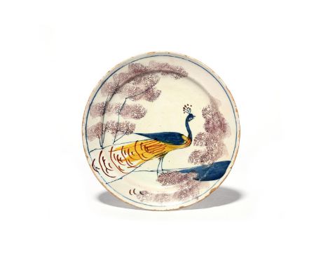 A Bristol delftware 'Farmhouse' plate  c.1720-30, painted with a bold peacock in yellow, blue and red, standing between spong