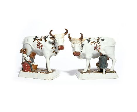 A pair of Delft cows  18th/19th century, each standing four square on a rectangular base with head slightly turned, being mil