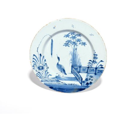 A delftware plate  c.1730-50, painted in blue with a strutting bird reaching up to a tall millet spray, a zigzag fence behind