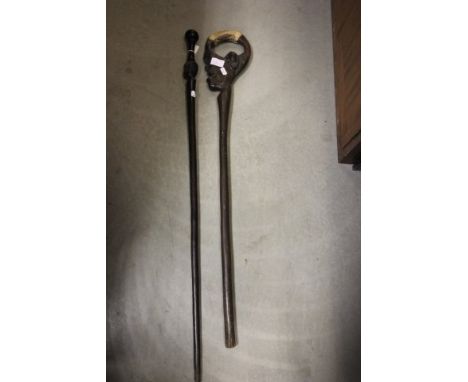 A Tribal African Walking Stick with the handle in the form of an Ethnic Man with skin cover grip together with another Africa