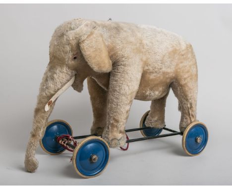 Elefant auf Rädern (Steiff, wohl 50er J.), "Reit-Elefant" m. Zugstimme, Knopf vorhanden,Gestell m. vier blauen Rädern aus Met