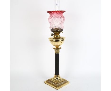 An early 20th century brass duplex Corinthian column oil lamp, with cranberry glass shade and chimney, height 74cm 